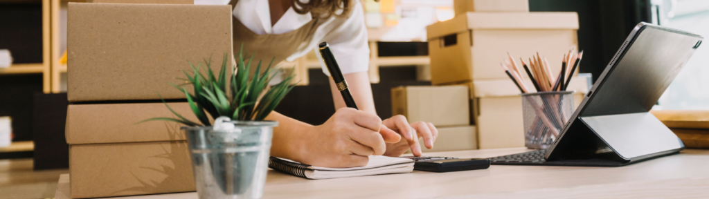 Person writing and making calculations using a calculator at a desk.